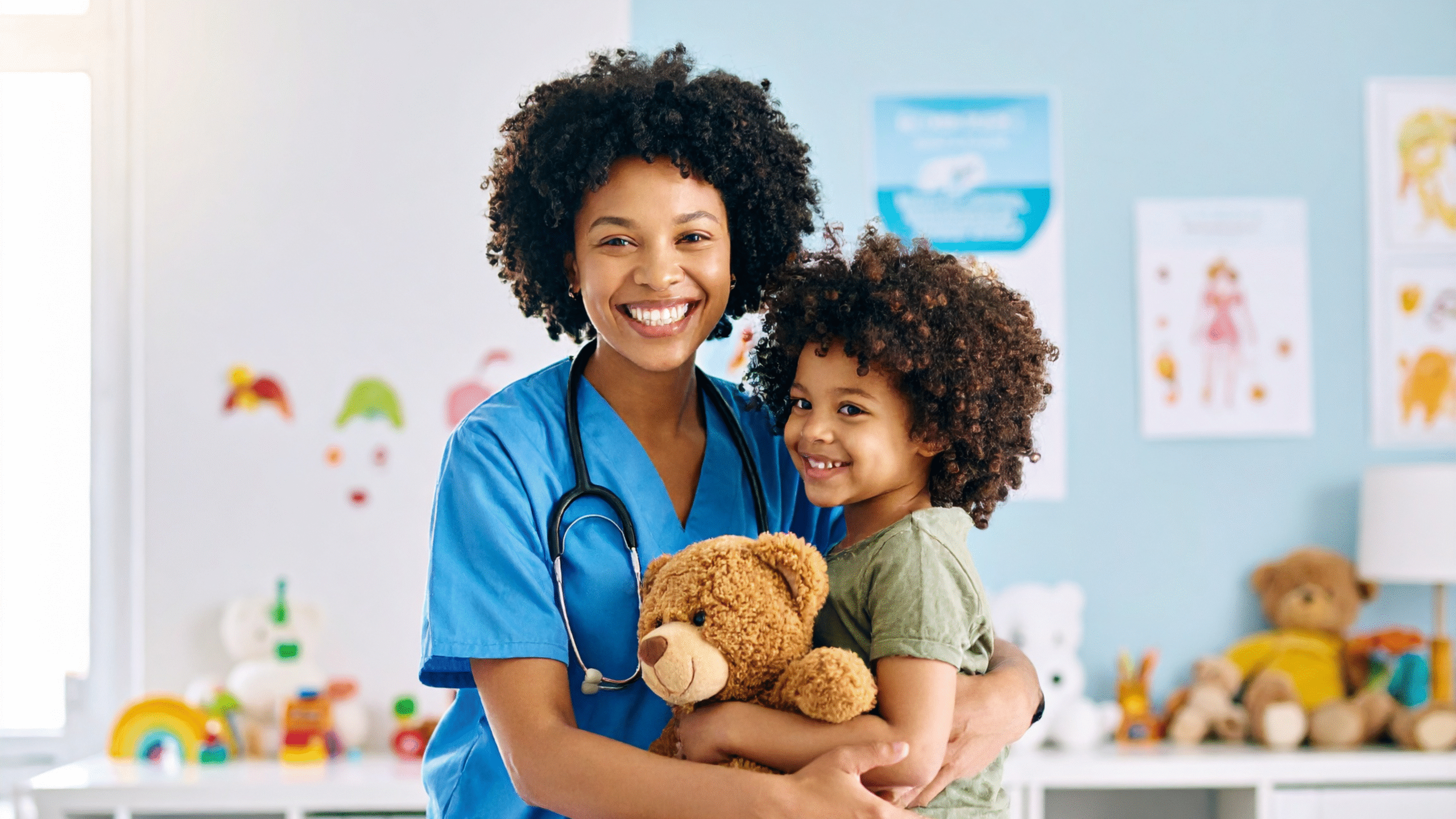 Doctor and pediatric patient hug with stuffed bear in hand.