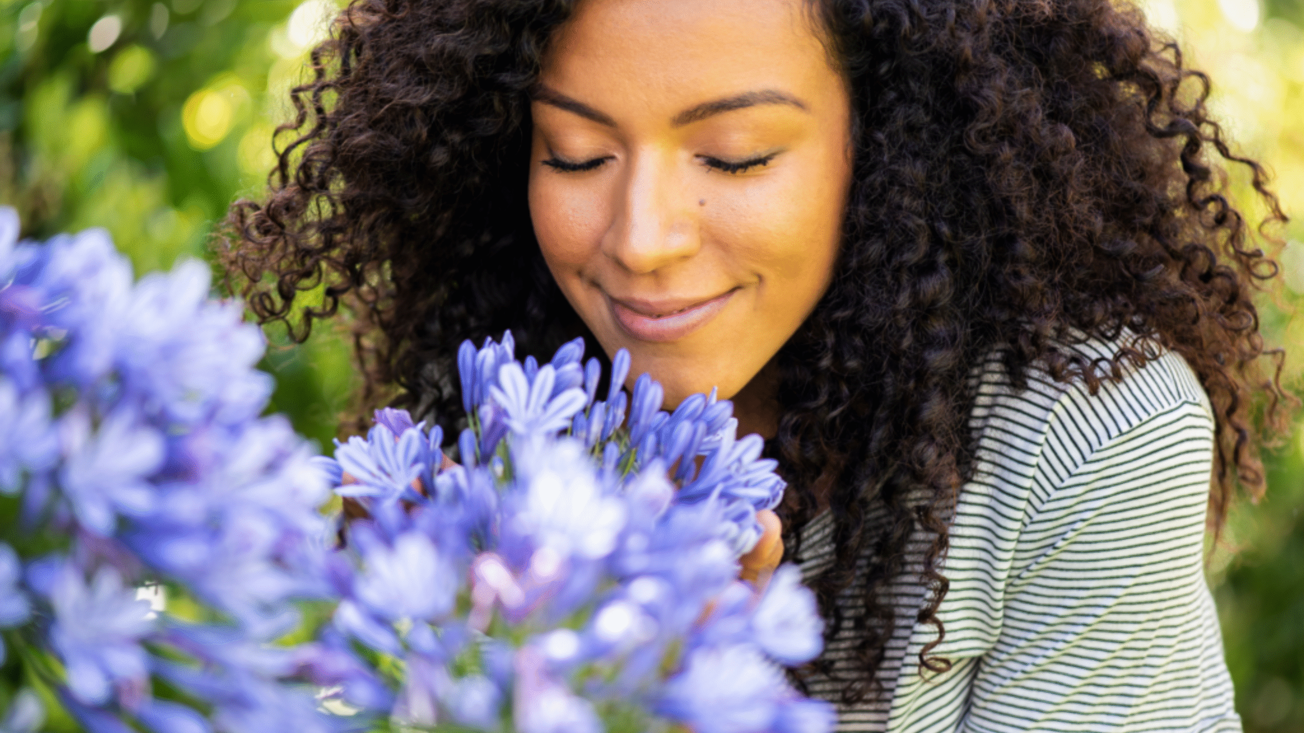 Woman smells purple flowers with a smile