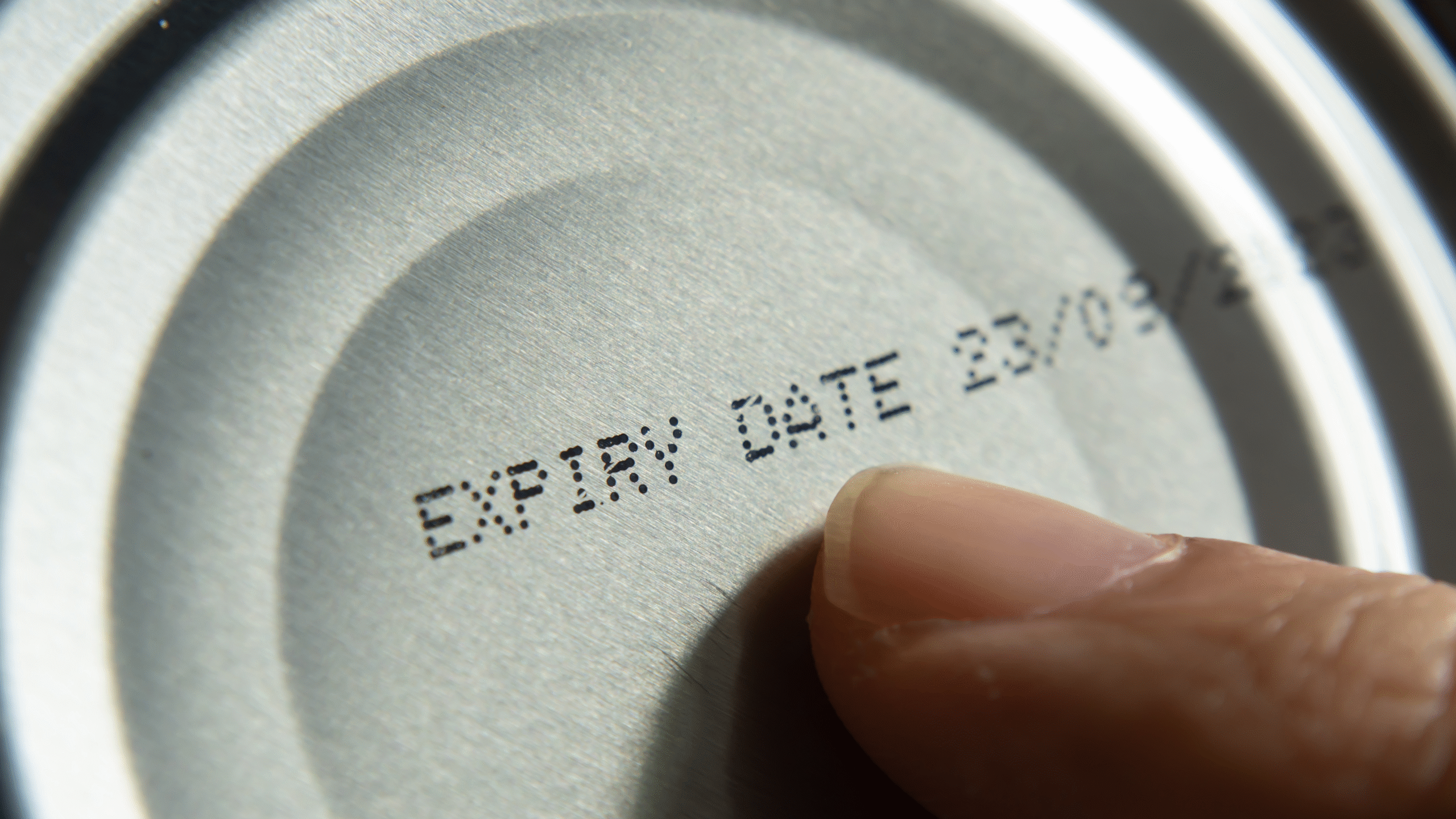 pointing to expiration date on can of food
