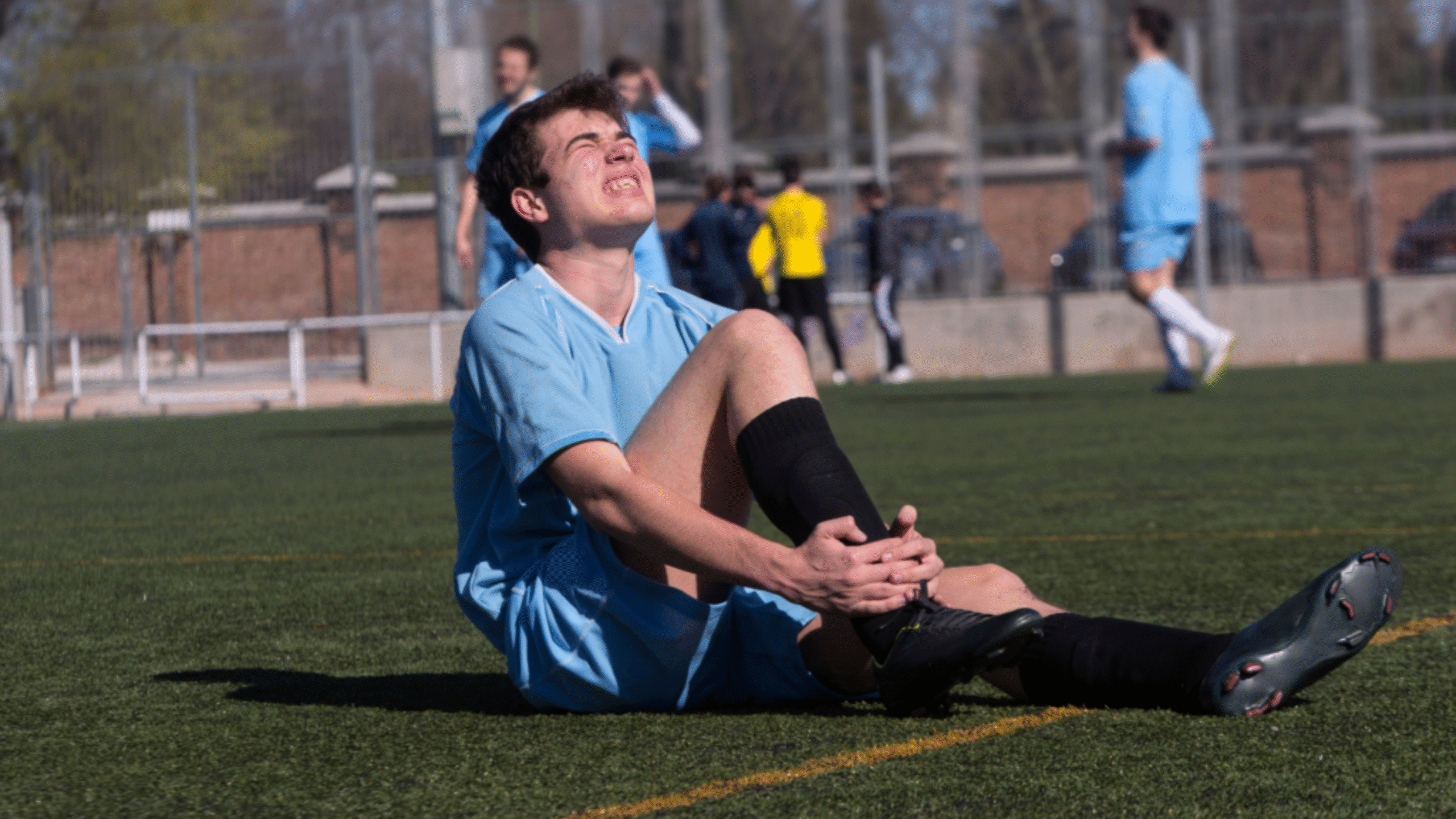 child with knee injury in pain on soccer field