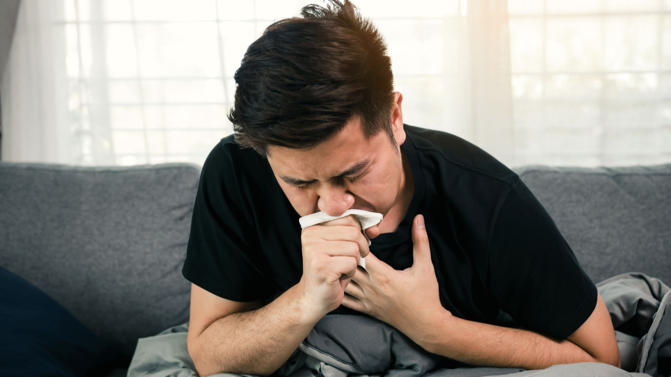 man coughs hard into napkin