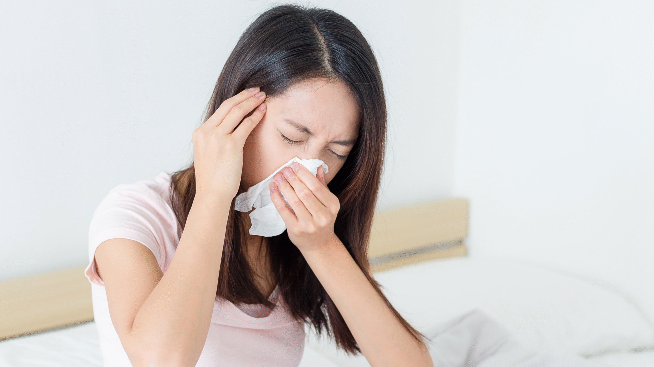 lady sneezing and blowing nose in bed