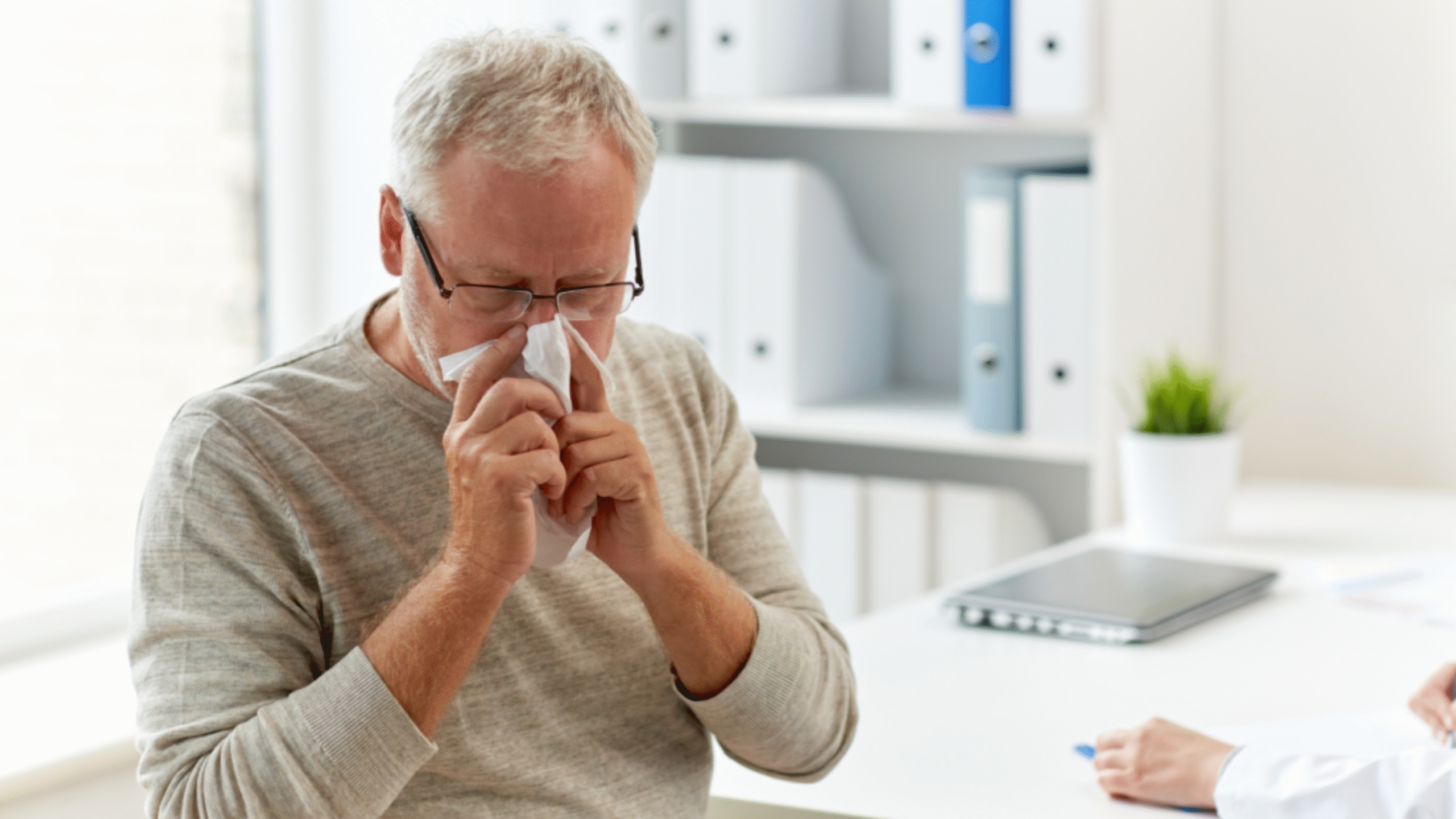 man blows his nose into a tissue