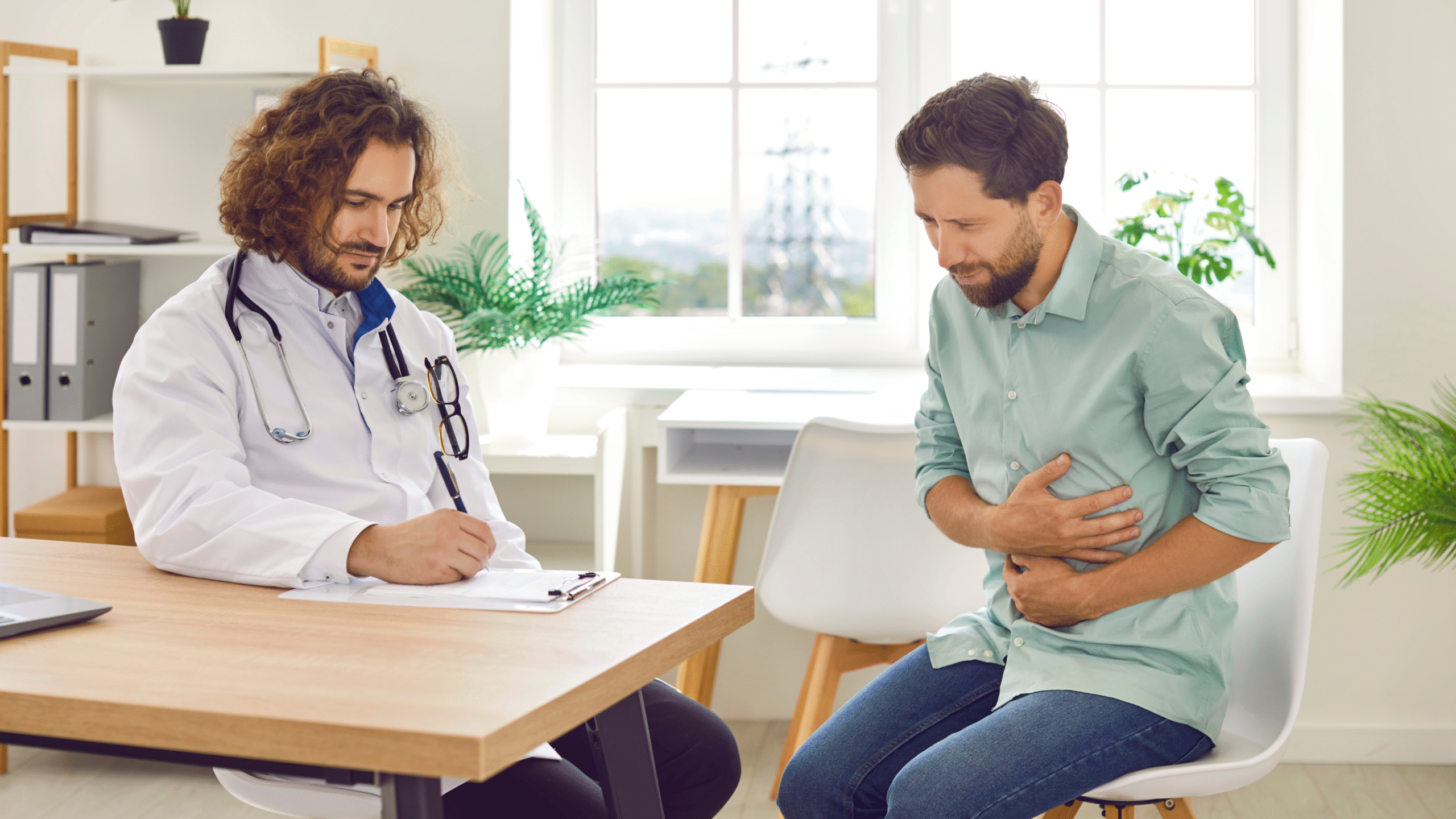 man with extreme stomach pain speaking with doctor