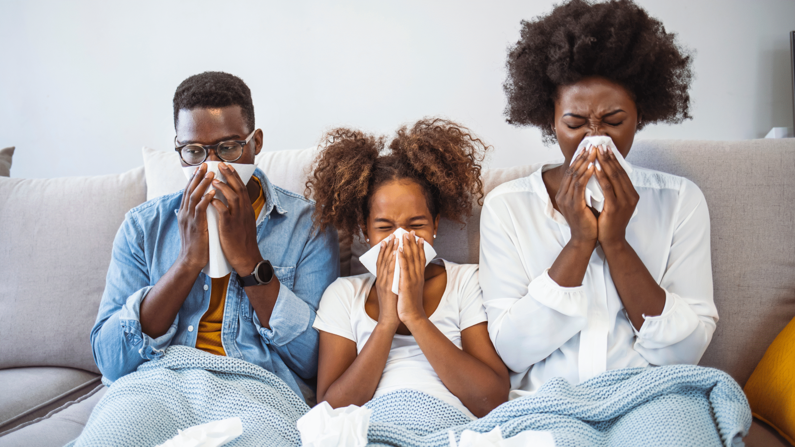 family sick on the couch blowing their nose