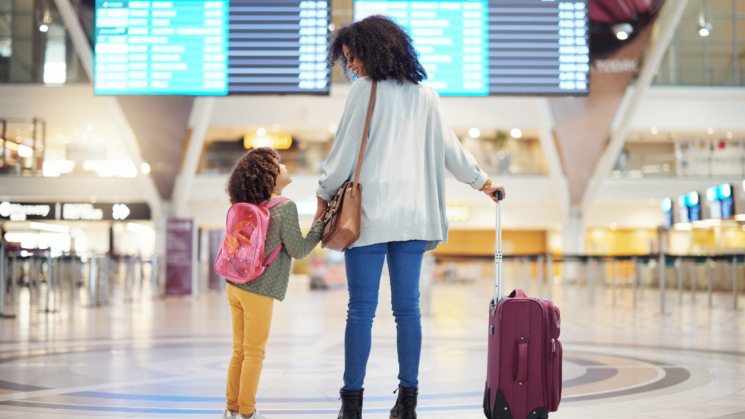 mother and daughter walk through airport