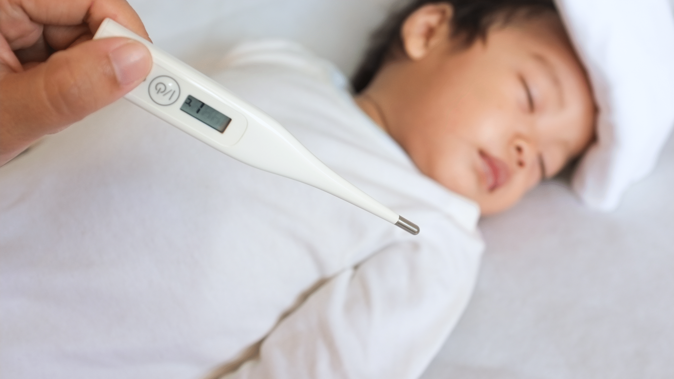 thermometer over a child with high fever laying in bed