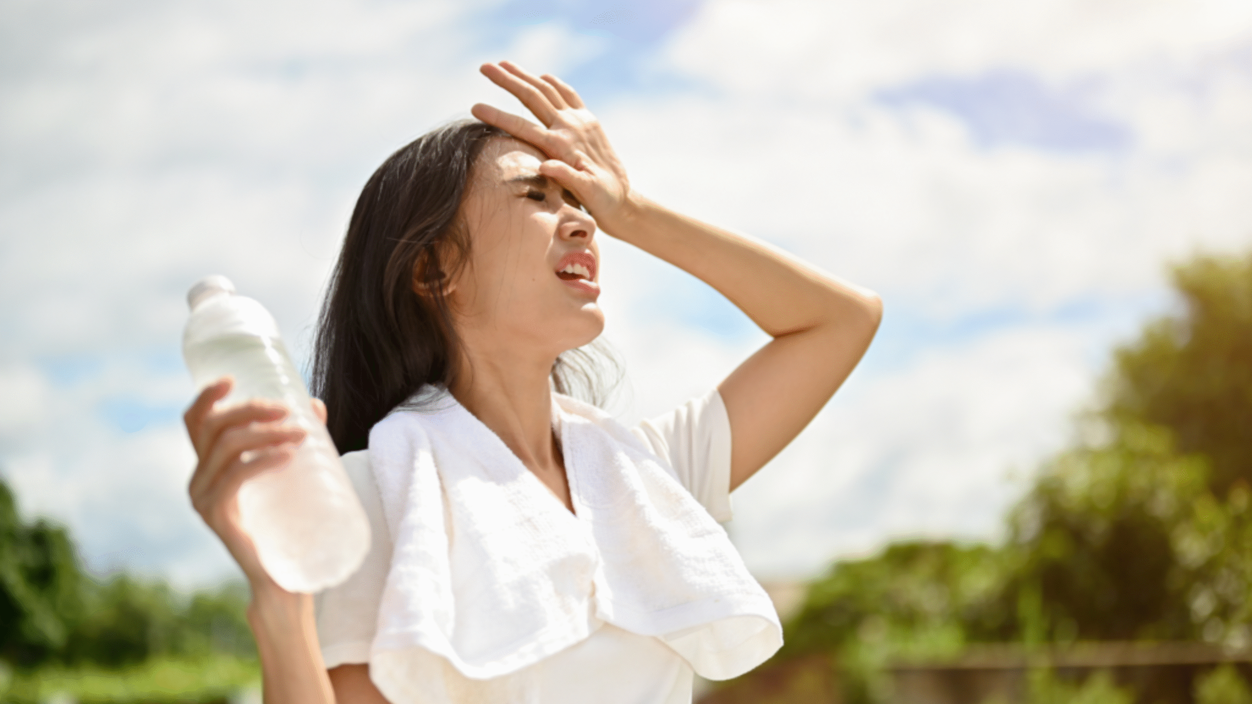 woman in extreme heat outdoors with towel and water